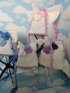 two crocheted unicorn hats sitting on top of a blue and white blanket next to each other