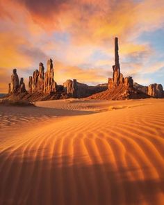 the desert is covered in sand and rocks at sunset with colorful clouds above it,