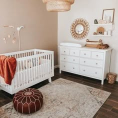 a baby's room with a white crib, dresser and mirror on the wall