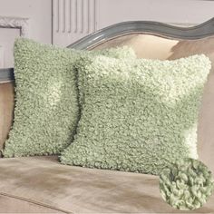 two green pillows sitting on top of a couch next to a pillow with ruffled edges