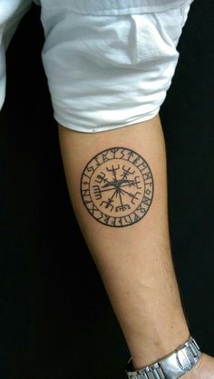 a man's arm with a compass tattoo on it