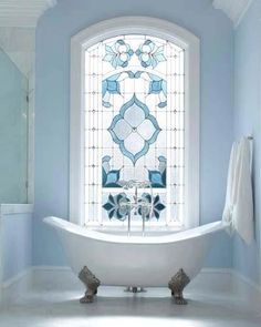 a white bath tub sitting under a window in a bathroom