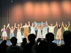 a group of people standing on top of a stage with their arms in the air