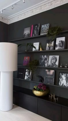 a living room with black walls and pictures on the wall, including a white lamp