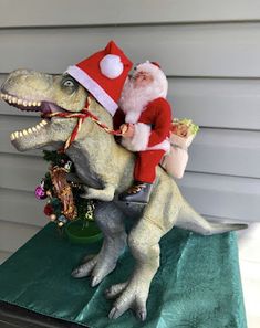 a santa clause riding on the back of a t - rexe with a christmas tree in its mouth