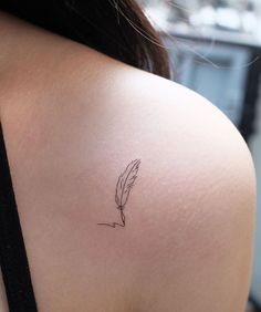 the back of a woman's shoulder with a small feather tattoo on her left arm