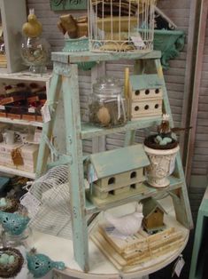 a birdcage filled with lots of birds on top of a white table next to shelves