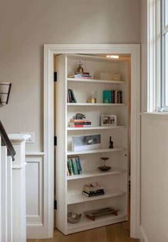 a white book shelf in the corner of a room next to a door and window