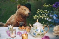 a stuffed bear sitting at a table with tea cups