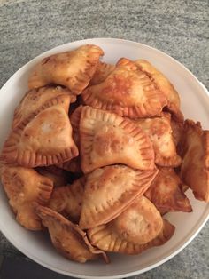 a white bowl filled with dumplings on top of a table