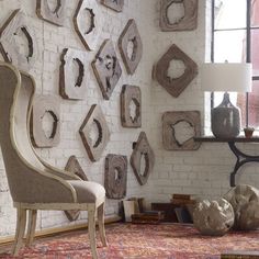 a chair sitting in front of a white brick wall filled with wooden frames on it