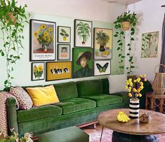 a living room filled with green couches and pictures on the wall above them, surrounded by potted plants