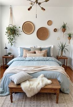 a bed with blue sheets and pillows on top of it next to two planters