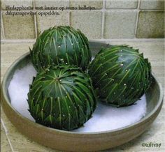 three green artichokes in a bowl on the counter