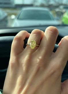 a close up of a person's hand with a ring on their finger in front of a car