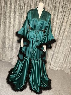 This vintage Emerald Green Hollywood inspired long robe is handmade from a super soft slight stretch satin with a marabou feather trim and matching belt. The perfect robe to strut around the house in, for a photoshoot, for as a stunning bridal wedding robe. Also available in a long version and other colours available. Can be customised in any way, please just message me with your ideas! All items can be custom made to fit your measurements. Please allow 7-14 working days for your item to be made and posted to you, however if you require your items for a certain date please just send me a message and I'll see what I can do! 70s Feather Robe, Teal Velvet Robe, Old Hollywood Satin Robe, Sheer Robe Green, Satin Ruffle Robe, Womens Robe Fancy, Old Hollywood Glamour Robes, Luxury Satin Party Robe, Luxury Fitted Formal Robe