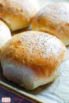 four rolls sitting on top of a pan covered in sesame seeds