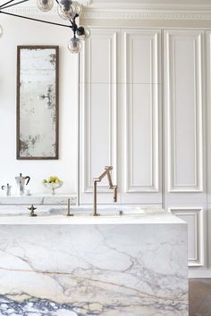 a kitchen with marble counter tops and white cabinets in the background, along with an ornate chandelier