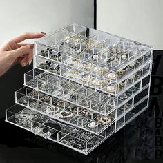 a person's hand is pointing at a jewelry organizer