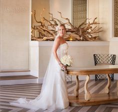 a beautiful woman in a wedding dress standing next to a table with flowers on it