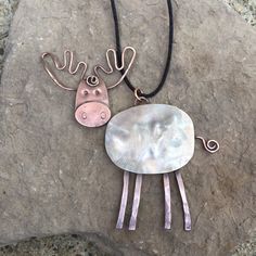 a necklace with two different designs on it sitting on top of a rock next to a black cord