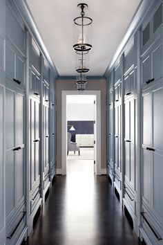 an empty hallway leading to a bedroom with blue walls and white trim on the doors