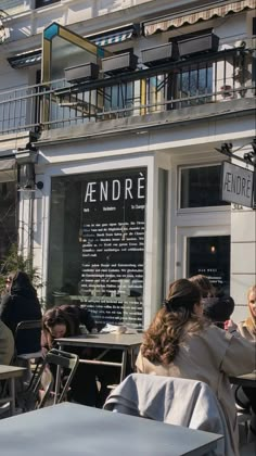 people sitting at tables in front of a restaurant