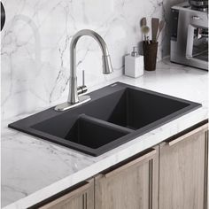 a kitchen sink with two faucets on top of it and marble counter tops