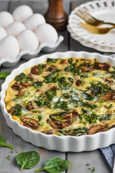 an egg and spinach quiche in a white pie dish on a wooden table