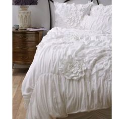 a white bed with ruffled bedspread and pillows