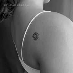 the back of a woman's shoulder with a small sun tattoo on her left arm