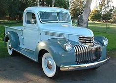 an old blue truck is parked on the street