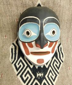 a mask is hanging on the wall in front of a carpeted area with a black and white pattern