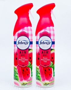 two bottles of air freshener sitting side by side on a white surface with watermelon slices