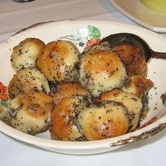 a white bowl filled with bread rolls on top of a table next to a plate of food