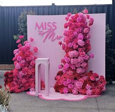 a pink display with flowers on the ground and a sign that says miss me next to it