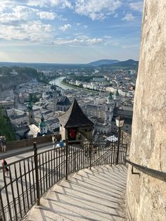 stairs lead down to the top of a hill with a view of a city in the distance