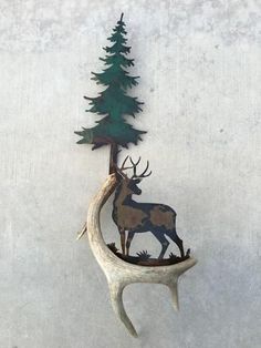 a deer is standing next to a pine tree on a white wall and it's antlers are hanging from the side