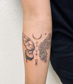 a woman's arm with a tattoo on it that has two wings and a crescent