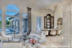 a living room filled with white furniture and large windows overlooking the pool in front of it