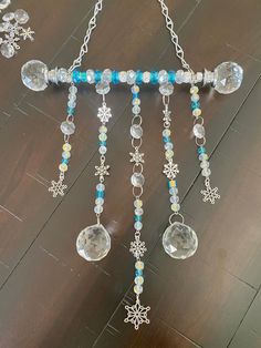 a wind chime hanging from a chain with beads and snowflakes on it