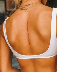 the back of a woman's white top with a tattoo on her left shoulder