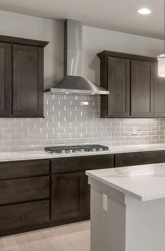 an empty kitchen with white counter tops and dark wood cabinets, along with stainless steel appliances