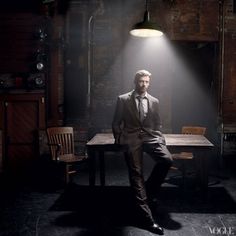 a man in a suit sitting at a table with a light shining on his head