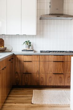 a kitchen with wooden cabinets and white tile backsplash, wood grain flooring