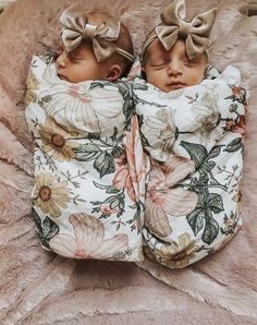 two baby babies wrapped in blankets with bows on their heads are laying down next to each other