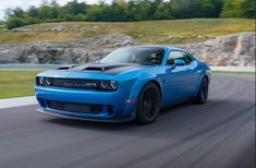 a blue dodge demon driving down a road