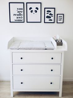 a white dresser with two pictures above it and a baby crib in the middle