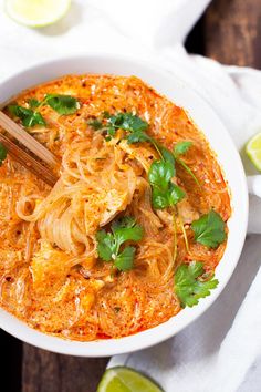 a white bowl filled with noodles, meat and garnished with cilantro