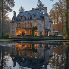 a large stone house sitting on top of a lush green field next to a lake